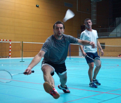Deux joueurs disputant un match de badminton en salle
